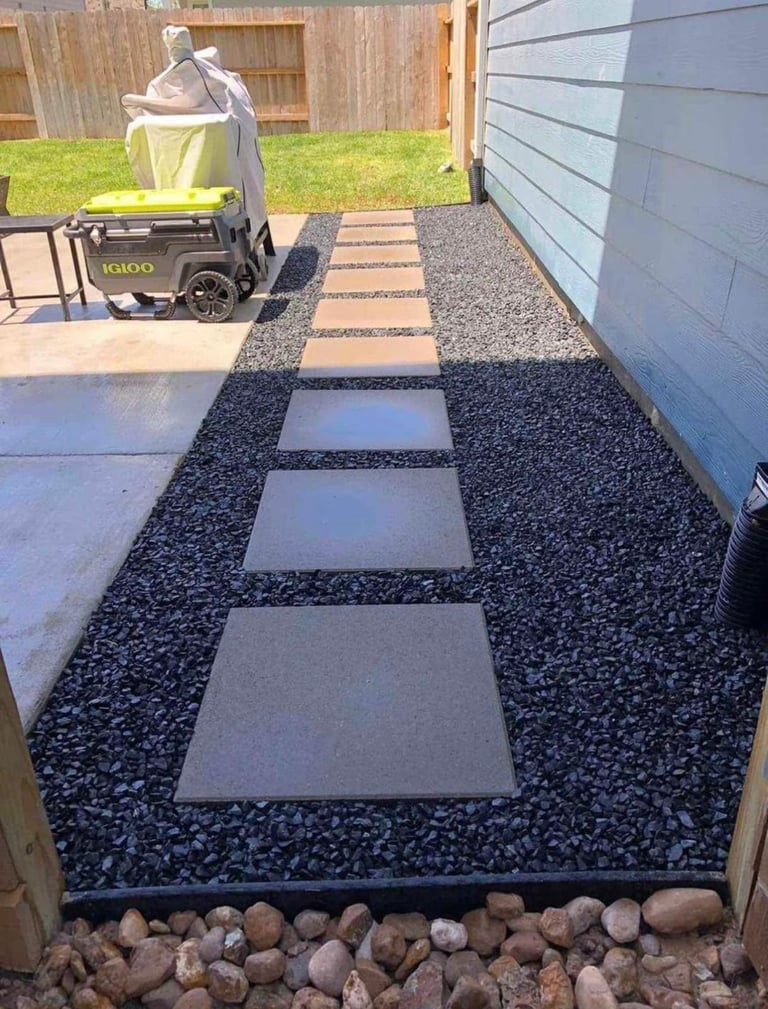 Residential driveway with alternating gray concrete pavers and dark gravel border, leading to a garage with a portable generator
